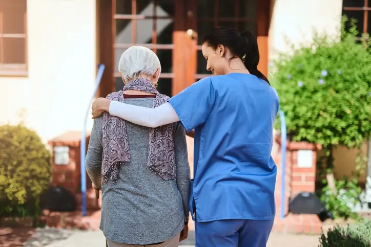 A senior woman and a nurse going for a walk together in a skilled nursing center garden in Bossier City