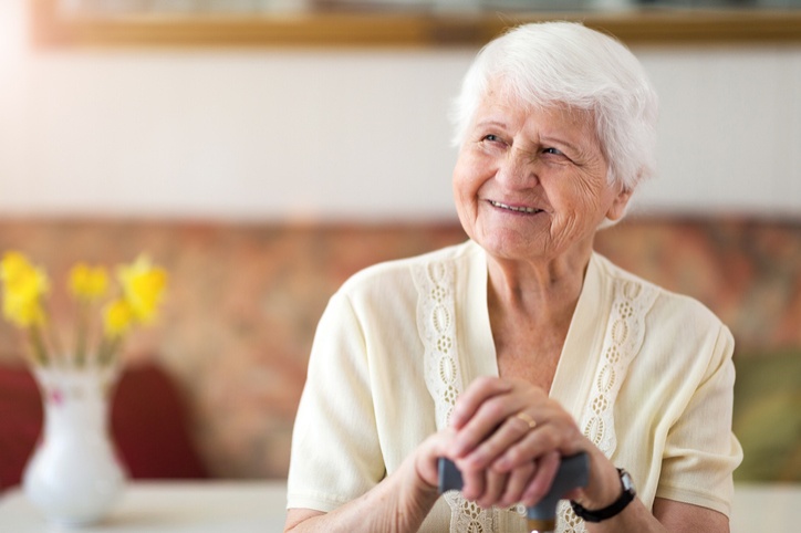 An older woman with a cane sits at a table in a palliative care facility in Bossier City, LA.