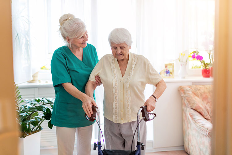 A hospice care nurse in Bossier City assists an elderly woman using a walker