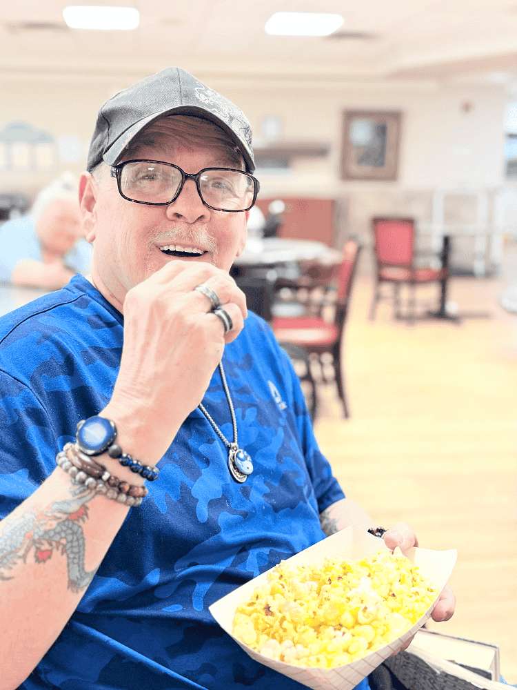 A man eating popcorn posing for a picture at a nursing home in Bossier City, LA