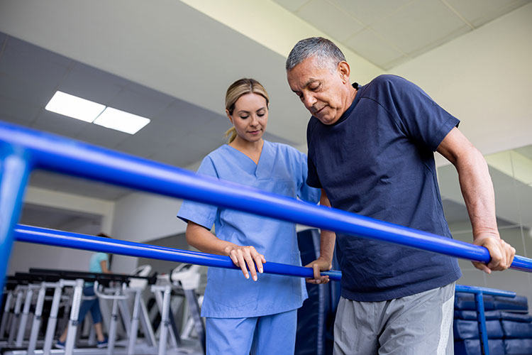A senior man uses the parallel bars during physical therapy in Bossier City, LA