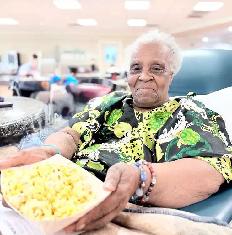 An aged woman offering popcorn to the cameraman at a nursing home in Bossier City, LA